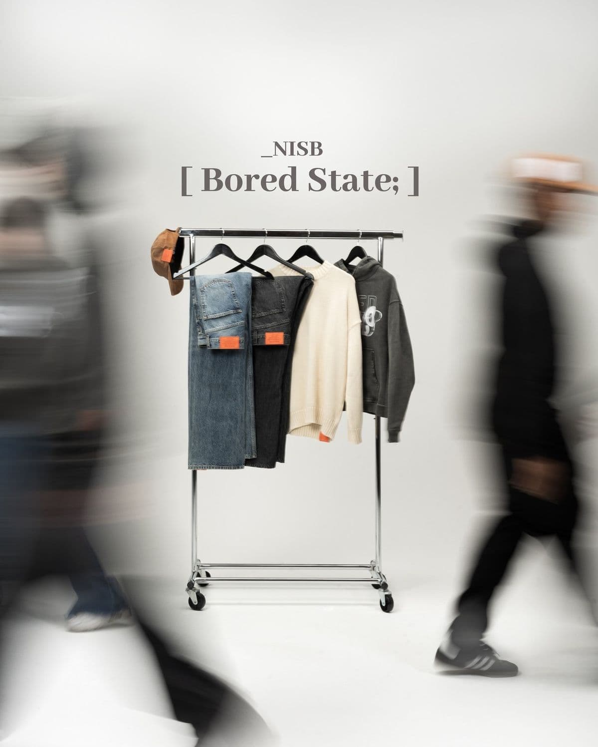 NISB clothing rail with denim, knitwear and a hoodie, blurred crowd passing